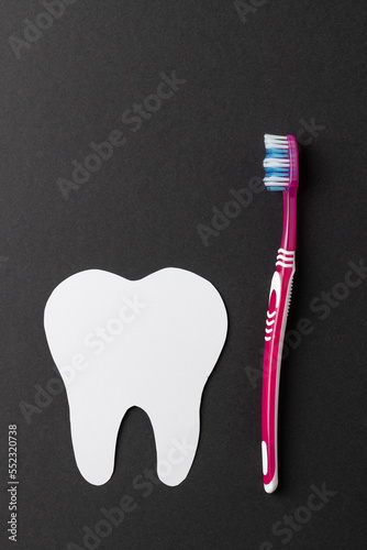 Vertical composition of white tooth and toothbrush on black background with copy space