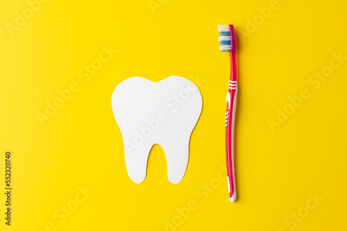 Composition of white tooth and toothbrush on yellow background with copy space