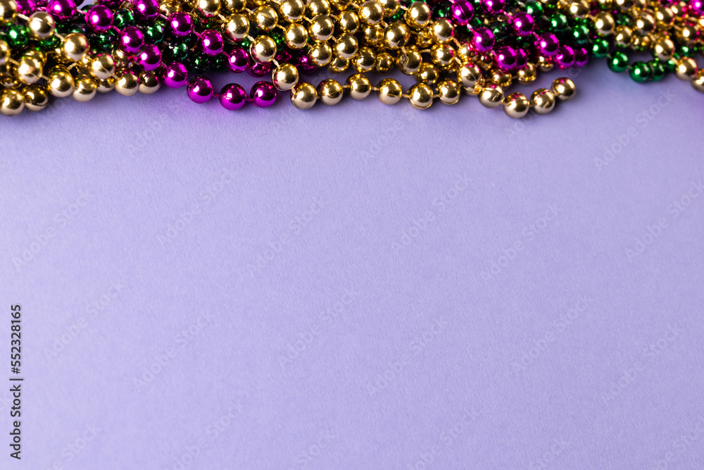 Composition of colourful mardi gras beads on lilac background with copy space - obrazy, fototapety, plakaty 