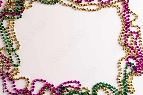 Composition of colourful mardi gras beads on white background, with copy space