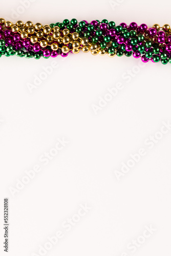 Composition of colourful mardi gras beads with copy space on white background with copy space