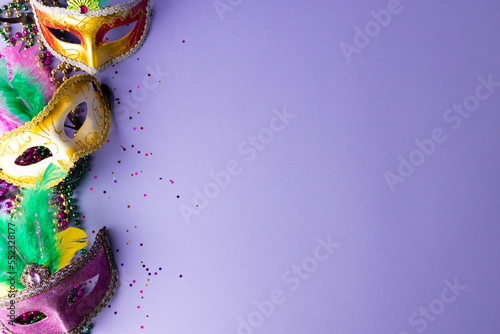 Composition of colourful mardi gras beads and carnival masks on blue background with copy space