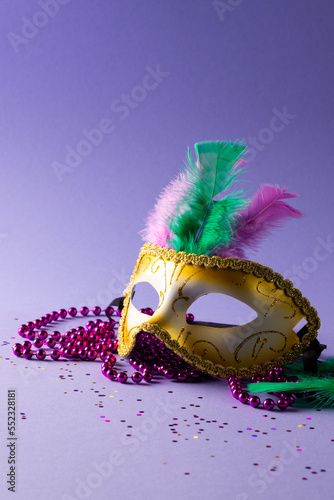Composition of colourful mardi gras beads and carnival mask on blue background with copy space