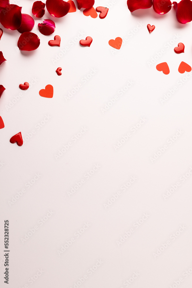 Composition of rose petals and hearts on white background