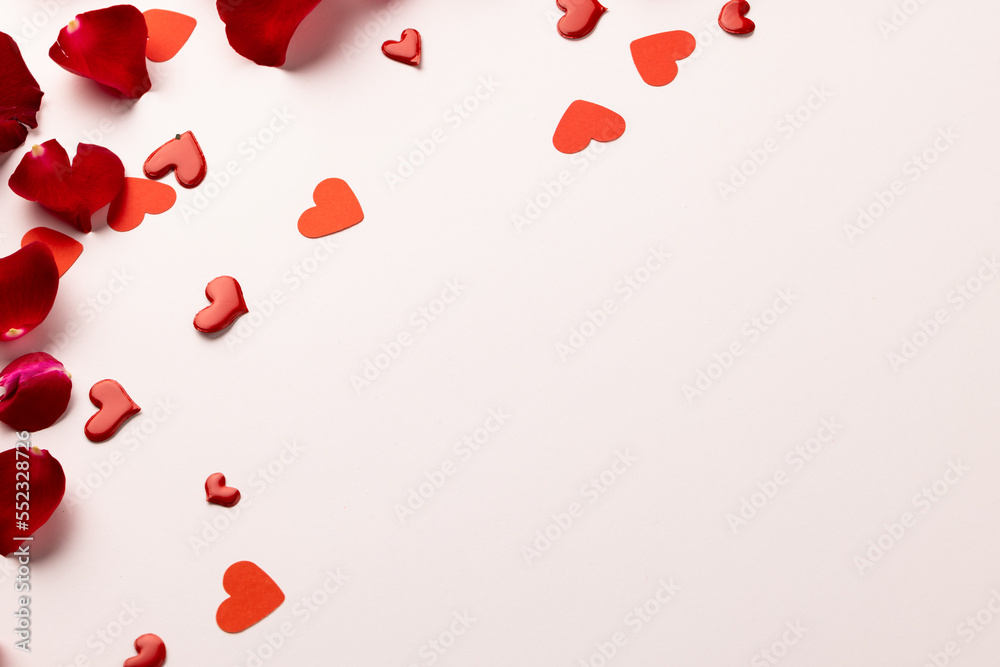 Fototapeta premium Composition of rose petals and hearts on white background