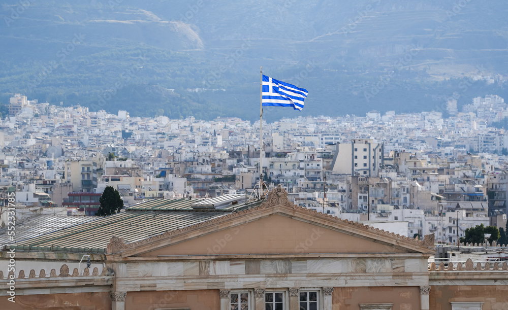Flag of Greece waving on top of Greek Parliament during a sunny day. Travel to Greece concept photo.