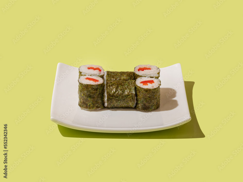 Sushi maki with tuna close up on white plate on green background Sushi maki with tuna close up on white plate on green background
