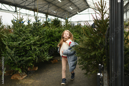 A girl running in a farm of Christmas norman trees