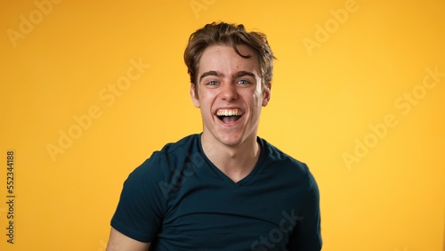 Portrait of young 20s man anticipating and then getting great success winner isolated over yellow background in studio. People sincere emotions, lifestyle concept. Looking at the camera © Robert Peak