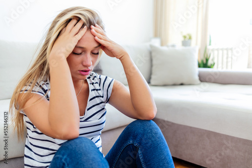 Anxious worried woman sitting on couch at home. Frustrated confused female feels unhappy, problems in personal life, quarrel breakup with boyfriend and unexpected pregnancy concept.