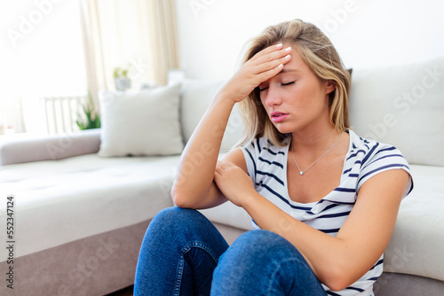 Anxious worried woman sitting on couch at home. Frustrated confused female feels unhappy, problems in personal life, quarrel breakup with boyfriend and unexpected pregnancy concept.