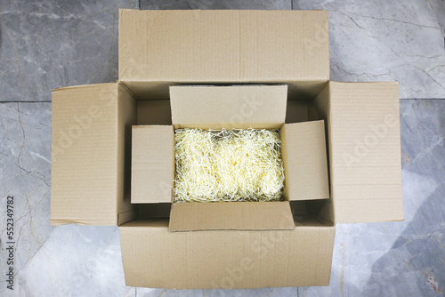 Small Realistic cardboard box opened top view with corrugated cardboard paper pieces instead of bubble wrap in big cardboard box in delivered parcel. Zero waste, multiply using cardboard boxes 