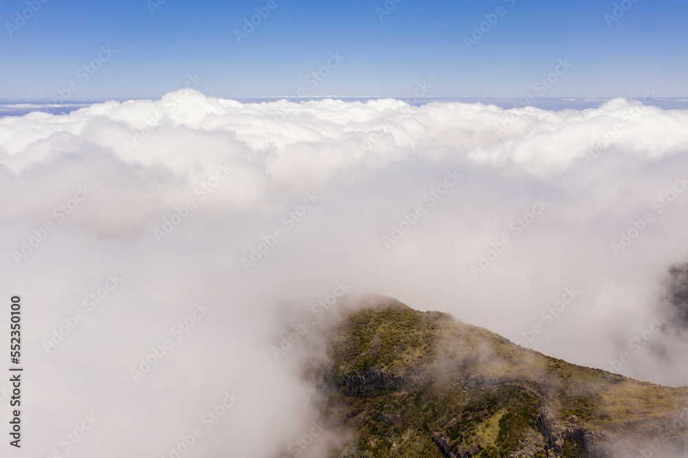 Fototapeta premium Drone view of mountain peak submerged in fog