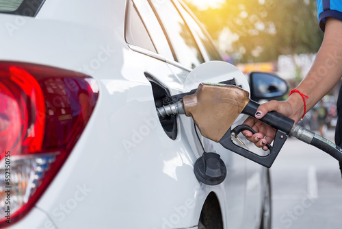 Closeup of people pumping gasoline fuel in car at gas station. Petrol or gasoline being pumped into a motor vehicle car.