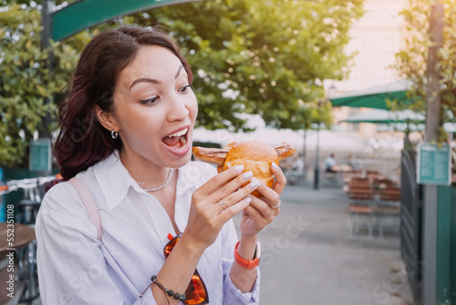 A happy girl eats an appetizing traditional German bratwurst hot dog with juicy sausage and seasonings