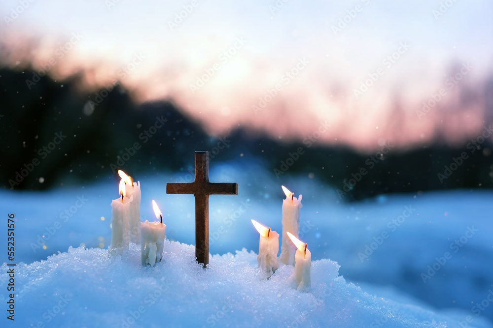 Christian cross and candles on snow, evening winter natural blurred