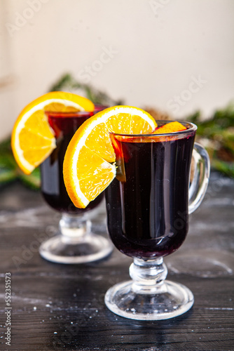 Glass of delicious glintwein or mulled hot wine, cinnamon, thread on vintage wooden background. photo