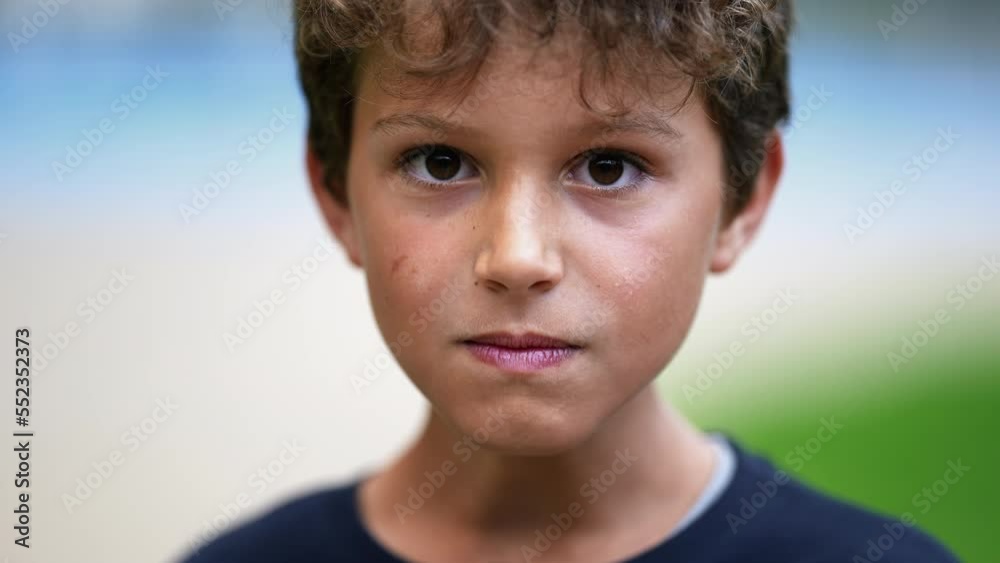 Upset male child looking at camera portrait with serious expression. One little preteen boy feeling anger