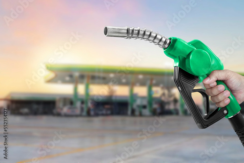 Holding a fuel nozzle against with gas station blurred background photo