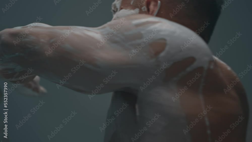 Athletic man posing naked while rubbing white clay over his muscular body Athletic man posing naked while rubbing white clay over his muscular body