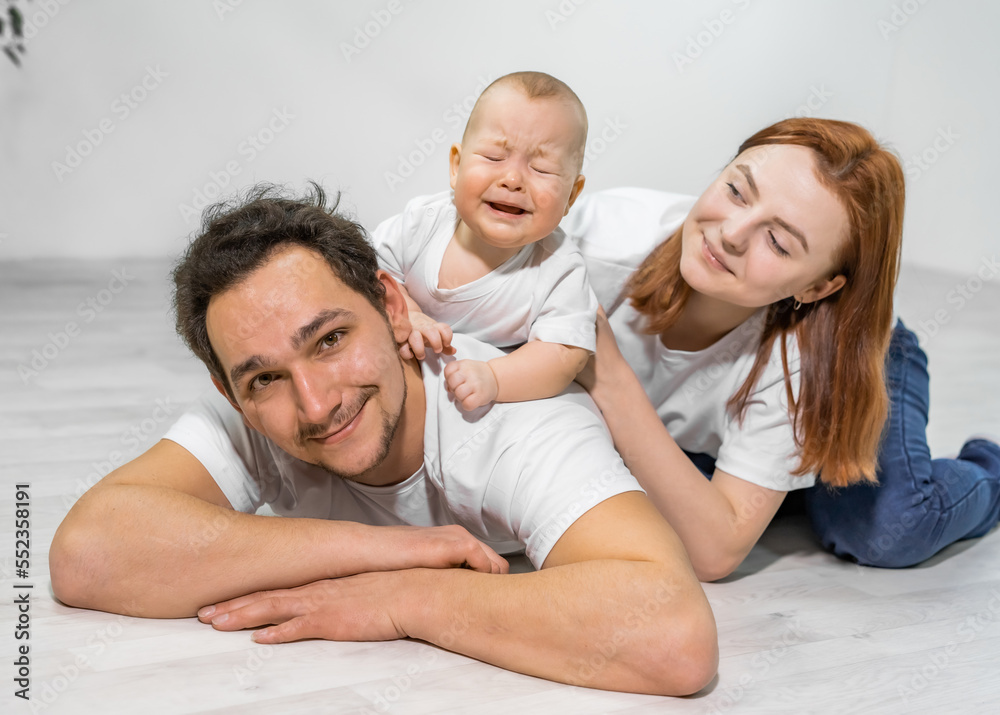 family in the studio or at home crawling on the floor with a baby. mom, dad, son play together family in the studio or at home crawling on the floor with a baby. mom, dad, son play together