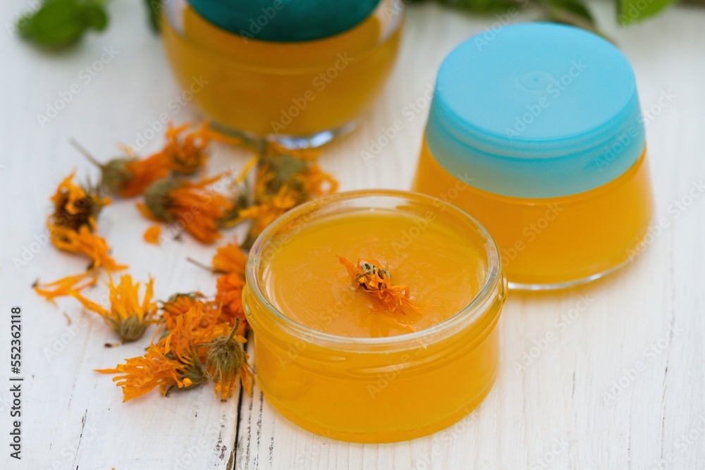 Making homemade organic calendula ointment, warm cream in small glasses.  Medicinal cream from dryed marigold flowers good for skin.. - obrazy, fototapety, plakaty 