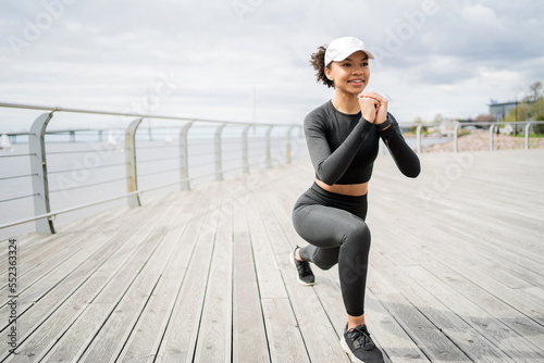 A woman does an active fitness workout on the street in sportswear and sneakers