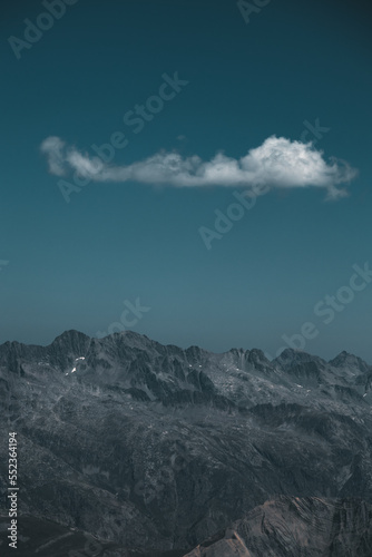a single cloud is hanging above the mountains in the alps, France © Bas