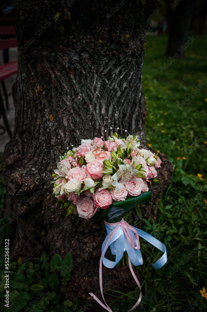 A pair of gold wedding rings on a bride's bouquet with colorful flowers