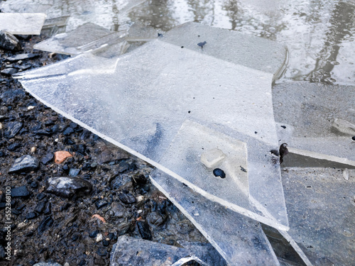 Broken ice shards in a puddle on the ground during wintertime