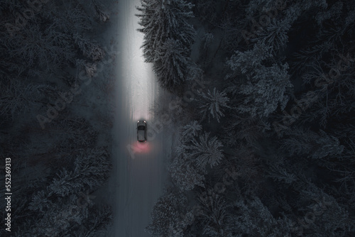 A passenger car moves along a forest winter road at night. Winter, Christmas theme