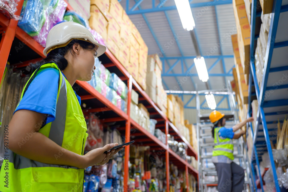 Asian female foreman talking to female worker Working inside a retail warehouse full of shelves with goods Female clerk holding a tablet to check inventory Asian female foreman talking to female worker Working inside a retail warehouse full of shelves with goods Female clerk holding a tablet to check inventory