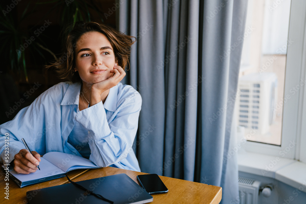 © Drobot Dean - Beautiful woman smiling while writing down notes in office © Drobot Dean - Beautiful woman smiling while writing down notes in office
