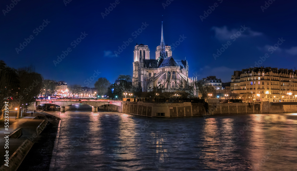 Illuminated Notre Dame de Paris Cathedral with the spire, before the fire at night, world most famous Gothic Roman Catholic cathedral in Paris, France