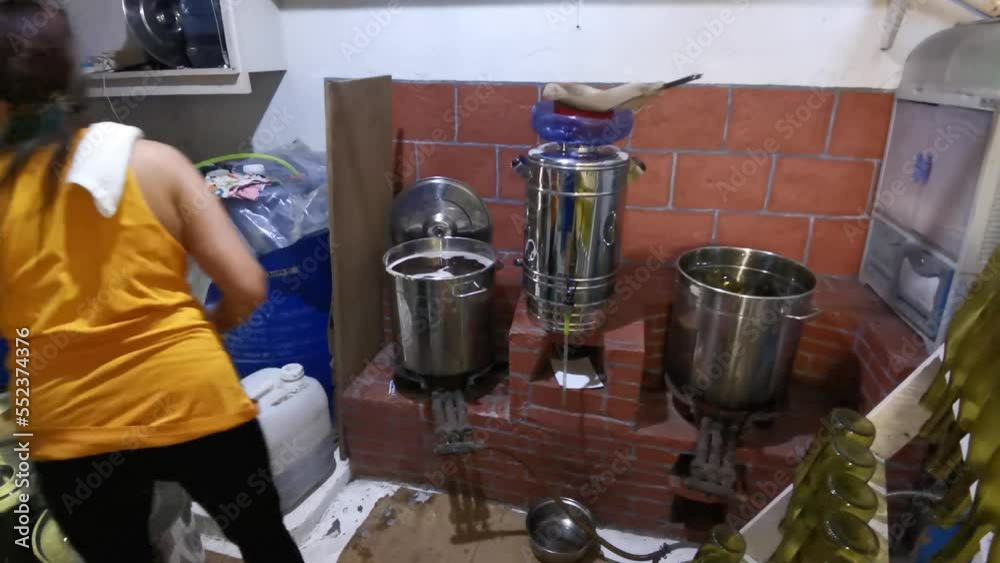 Asian woman straining boiling fermented fruit wine juice floating