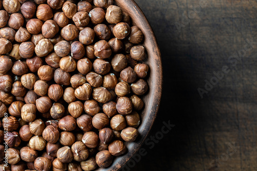 Dry hazelnuts in a ceramic plate on a wooden background. Heap of peeled hazelnuts kernels, top view, copy space for text