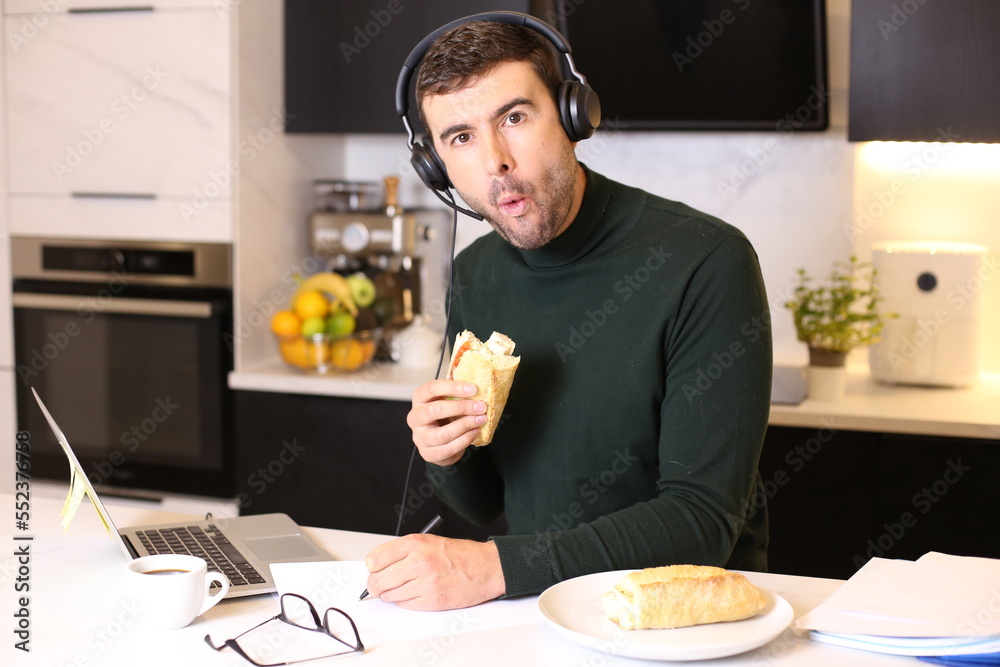 Busy man eating a sandwich while on conference call Busy man eating a sandwich while on conference call