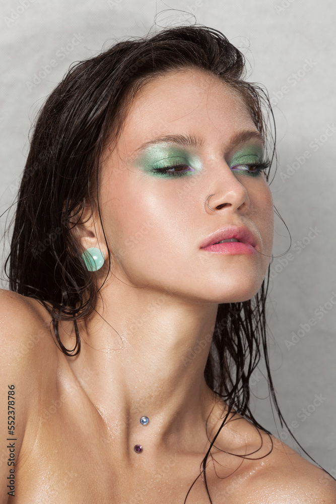 Close-up portrait of beautiful woman's purity face with green make-up. Model with wet clean shiny skin. Small drops on the skin. Close-up portrait of beautiful woman's purity face with green make-up. Model with wet clean shiny skin. Small drops on the skin.
