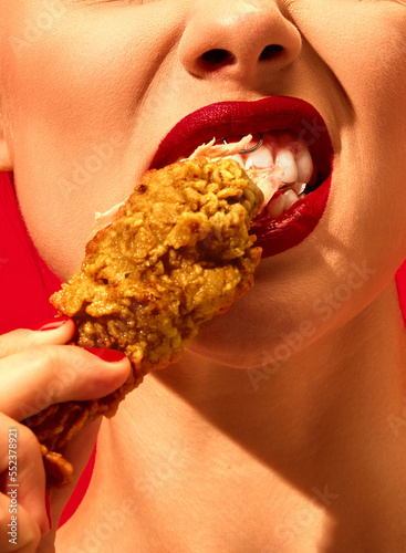 Photography Close-up cropped image of young woman eating fried chicken, nuggets over vivid red background