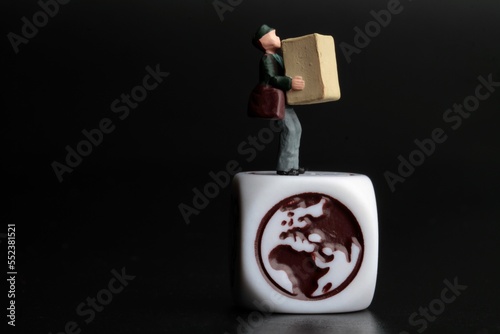 miniature figurine of a delivery man holding a parcel on a black background with icon on a dice