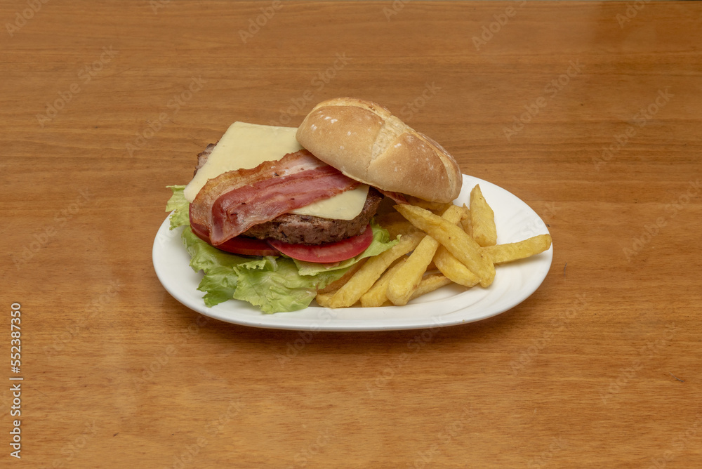 Beef burger with sliced cheese, lettuce, sliced tomato, slices of fried bacon and home fries