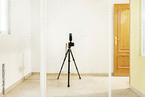 A self-photographed camera with tripod and flash on a sliding mirror door of a built-in wardrobe