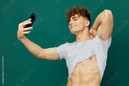 a handsome, sexy man takes pictures of his perfect abs on his phone