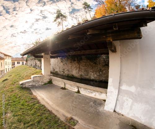 Borgo San Dalmazzo, Cuneo, Italy- December 01, 2022: The stone wash house in via Discesa Molino (descent mill) with the light and colors of autumn photo