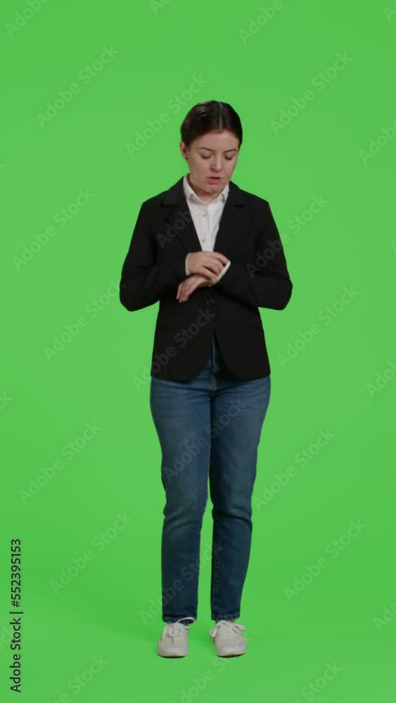 Vertical video: Front view of businesswoman looking at wristwatch to check time over greenscreen backdrop, running late and waiting. Impatient corporate worker standing over isolated green screen Vertical video: Front view of businesswoman looking at wristwatch to check time over greenscreen backdrop, running late and waiting. Impatient corporate worker standing over isolated green screen