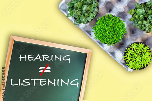 Hearing not equal listening written on chalkboard  with planting a few trees. Communication with understanding concept and soft skill idea