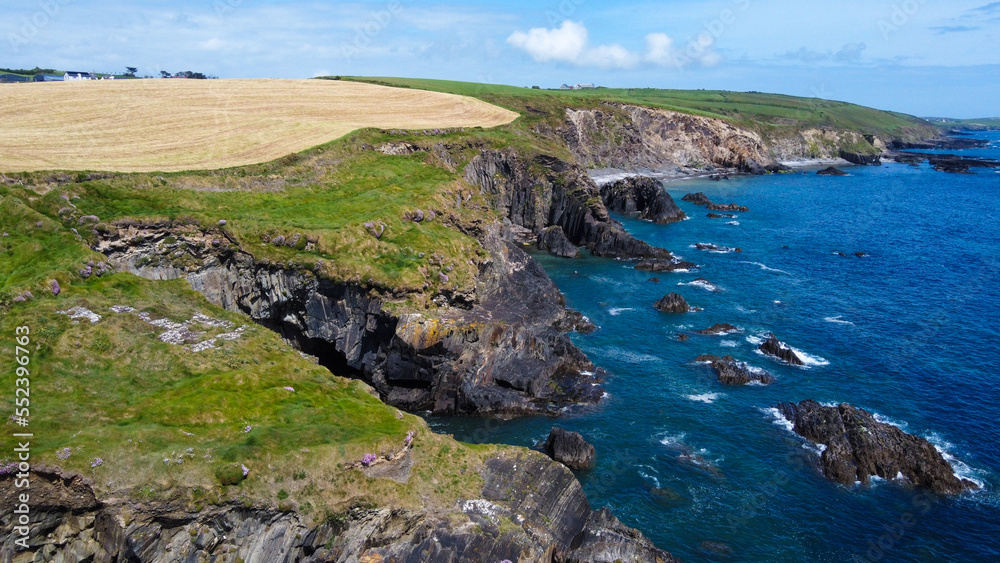Obraz premium Farm fields on the rocky shore of the Celtic Sea, south of Ireland, County Cork. Beautiful coastal area. Turquoise waters of the Atlantic. Picturesque stone hills. Drone photo. View from above.