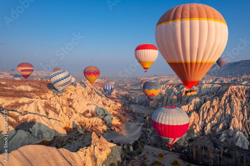 Aerial view amazing sunrise landscape in Cappadocia with colorful hot air balloon fly in sky over deep canyons, valleys. Concept banner travel Turkey