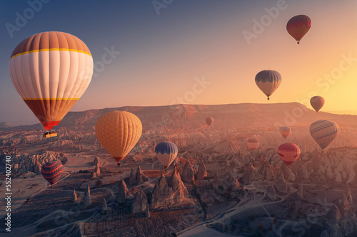 Landscape sunrise in Cappadocia with set colorful hot air balloon fly in sky deep canyons, valleys with sunlight. Concept tourist travel Goreme Turkey