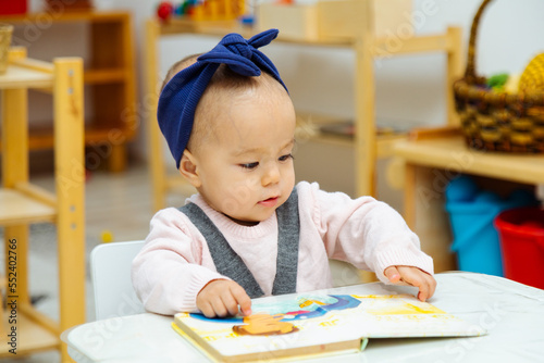 Toddler reading book by the table